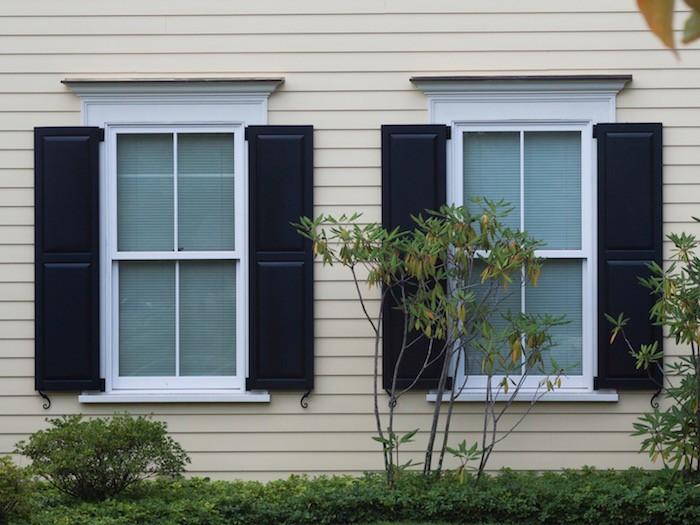 Outside house siding.  Two windows with blue shutters and white trim